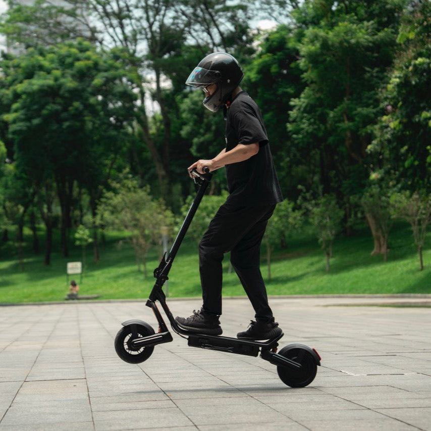Person riding a black electric scooter in a park
