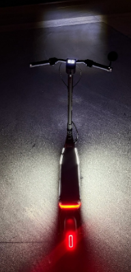 Rear view of an Apollo electric scooter at night with deck and brake light lit