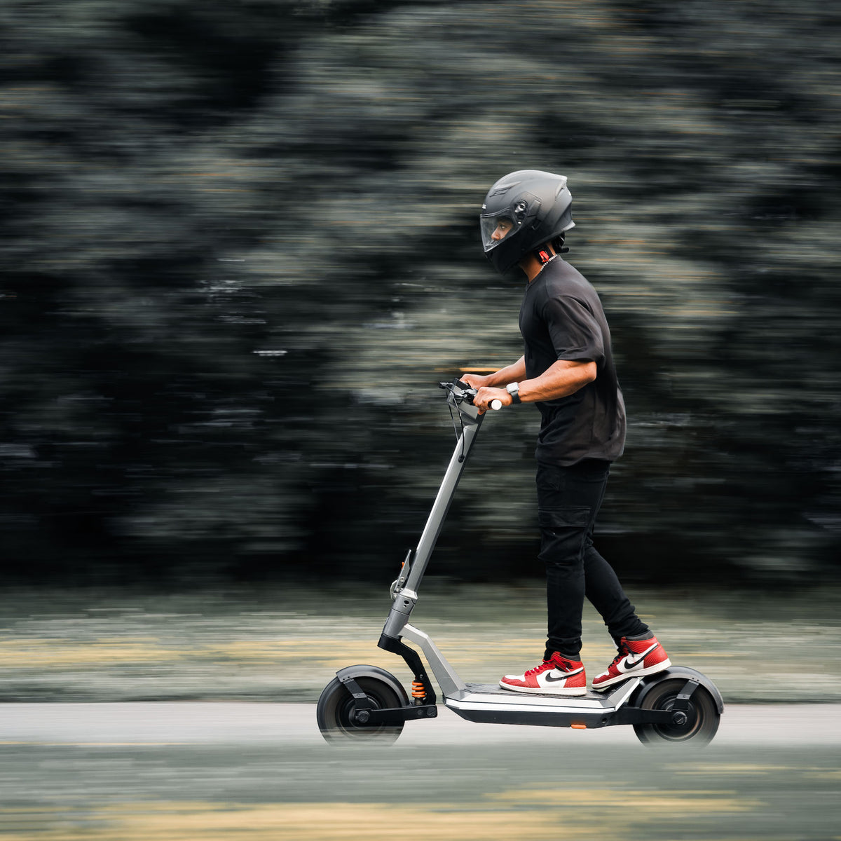 An individual riding the Apollo Pro fast e scooter on a road.